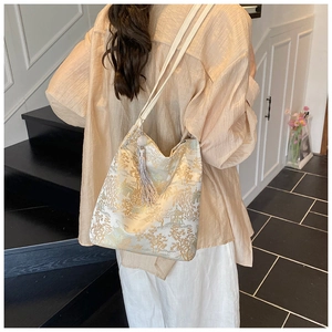 Detail of embroidered landscape patterns and silk tassel on the white shoulder bag