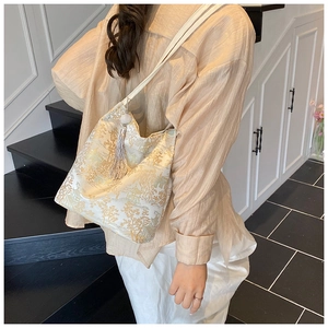 Close-up of white jacquard tote bag with traditional embroidery and long tassel charm