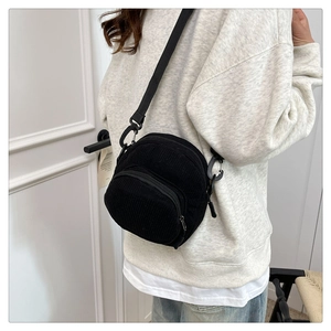 Detail of black corduroy crossbody bag with layered zippers and adjustable nylon strap