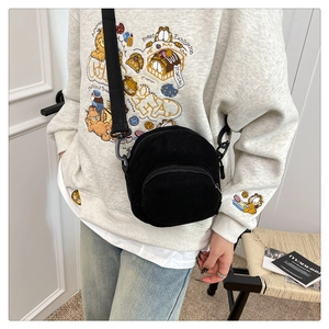 Detail showing the textured black corduroy fabric and adjustable strap of the square bag