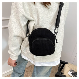 Detail of black corduroy mini crossbody bag showing striped texture and nylon strap