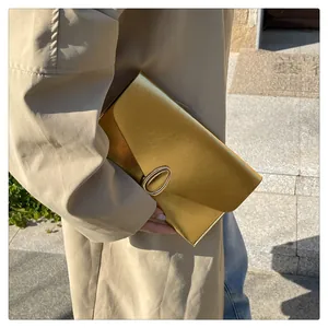 Détail d'une pochette dorée chic avec cadre rectangulaire et boucle métallique élégante