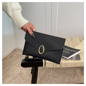 Détail d'une pochette enveloppe en cuir Saffiano noir avec boucle ovale en métal doré