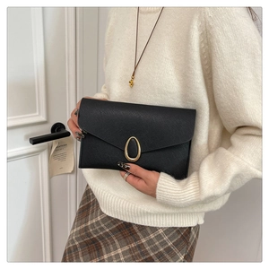 Détail d'une pochette enveloppe noire en cuir Saffiano avec boucle dorée ovale