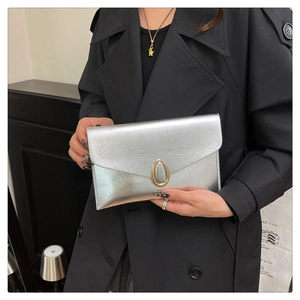 Détail de la pochette enveloppe argentée avec texture brossée et fermoir doré