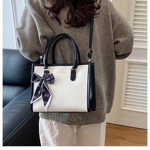 Detail view of large white snake-pattern tote bag with black trim and elegant silk scarf