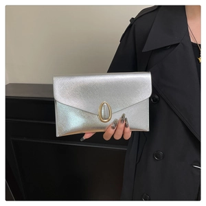 Détail de la pochette enveloppe argentée avec texture métal brossé et boucle dorée