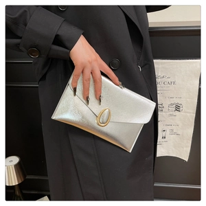 Détail de la pochette enveloppe argentée avec boucle goutte dorée et finition texturée