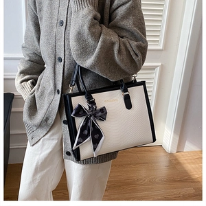 Détail du sac cabas imprimé serpent avec bordure contrastée et foulard en soie