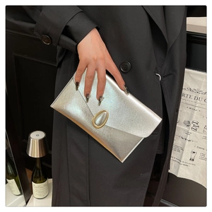 Pochette enveloppe argentée scintillante avec fermoir en métal tenue par une femme