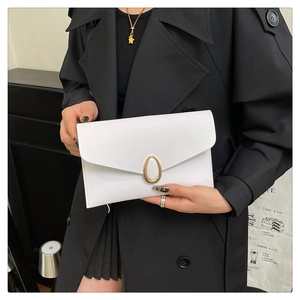Vue détaillée d'une pochette enveloppe blanche en cuir avec boucle dorée tenue par un mannequin