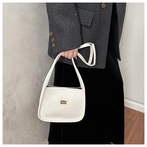 Macro shot of minimalist white leather underarm bag with gold logo and smooth finish