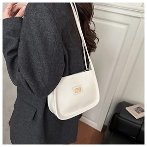 Close-up of minimalist white leather underarm bag with gold metal plate and slim straps