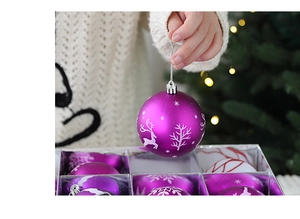 Close-up of purple Christmas ball with silver reindeer and snowflake glitter patterns