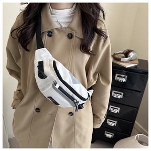 Close-up of white sporty crossbody bag with black adjustable straps on a model in trench coat