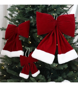 Gros plan de nœuds de Noël en velours rouge avec bordure en fourrure sur un sapin