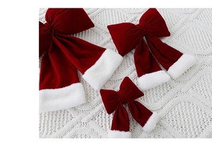 Trois nœuds de Noël en velours bordeaux avec bordure blanche sur tricot blanc