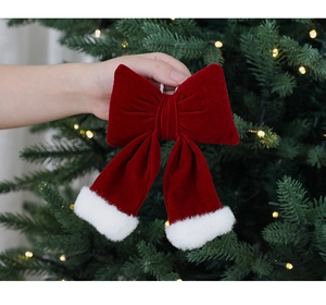 Détail d'un nœud de Noël en velours rouge avec bordure en peluche blanche sur sapin