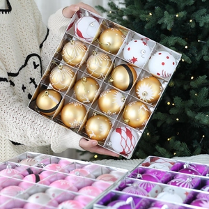 Hand holding transparent box of 16 assorted gold and white Christmas ball ornaments