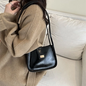 Chic black minimalist underarm bag with glossy finish and gold metal plate detail