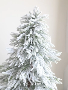 Detailed close-up of realistic white flocked artificial Christmas tree with dense snow effect