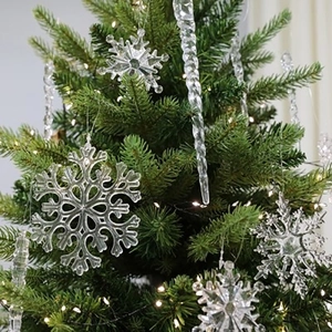 Copos de nieve y carámbanos de acrílico transparente en un árbol de Navidad verde con luces