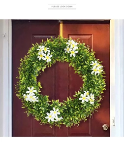 Détail d'une couronne printanière de feuilles vertes et fleurs blanches sur porte
