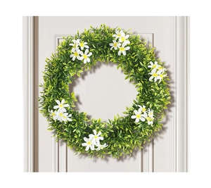 Détail d'une couronne de feuilles vertes artificielles avec fleurs blanches sur porte