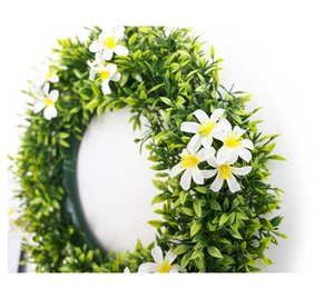 Détail de couronne verte artificielle avec de petites fleurs blanches et étamines jaunes
