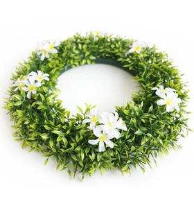 Détail de la couronne verte artificielle avec de petites fleurs blanches pour décoration
