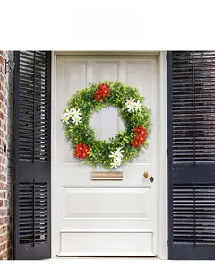 Detail of colorful artificial eucalyptus wreath with red and white flowers on a white door