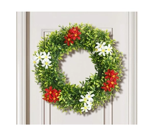 Close-up of artificial eucalyptus wreath with red and white flowers on white wooden door