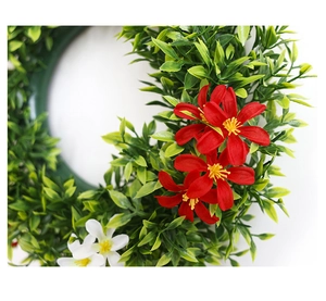 Macro shot of colorful artificial eucalyptus wreath with red flowers and green leaves