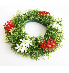 Macro detail of artificial eucalyptus wreath with small red and white flowers