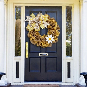 Handcrafted yellow and brown burlap wreath with bee festival bow on a dark blue front door
