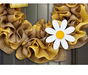 Detail of a handmade yellow and natural burlap wreath with a white daisy floral accent