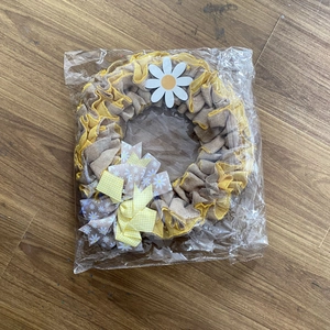 Detail of burlap Fourth of July wreath with daisy and checkered bow in clear packaging