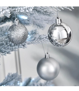 Palline di Natale argento con finiture glitter, lucide e opache appese a rami innevati