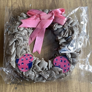 Detail van jute krans met roze strik en lieveheersbeestjes op houten bodem