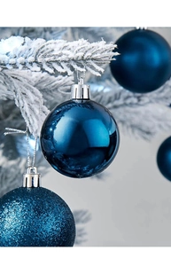 Dettaglio di pallina di Natale blu reale opaca su un ramo di albero innevato e bianco