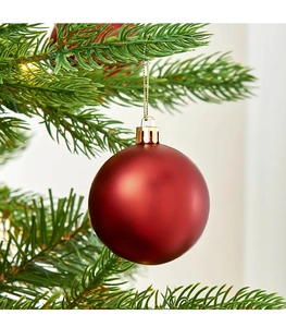 Primo piano di una pallina di Natale rossa opaca da 8 cm appesa a un ramo di pino verde