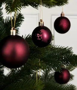 Macro shot of matte and shiny burgundy Christmas ball ornaments on green pine tree