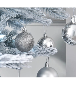 Primo piano di palline di Natale argentate con finiture glitterate e opache su rami innevati