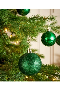Dettaglio di palline di Natale verdi opache e lucide appese a un ramo di pino