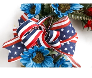 Close-up of blue artificial sunflowers and American flag ribbon on patriotic wreath