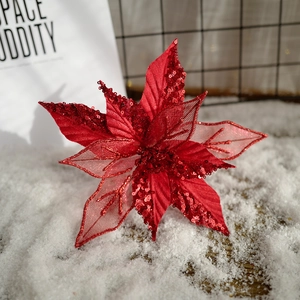 Rote Weihnachtsblume mit Pailletten und Hohlnetz auf künstlichem Schneehintergrund