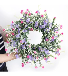Detail of spring wreath with purple wildflowers and green leaves for home wall decor