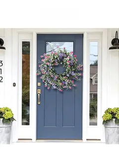 Detail of pink and purple floral wreath with green leaves on blue wooden front door
