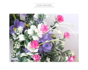 Close-up of spring wreath featuring purple and pink wildflowers with green leaf texture
