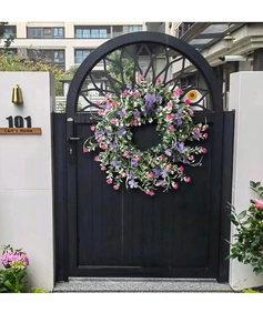 Detail of spring floral wreath with purple wildflowers and green leaves on a black door